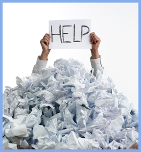 Picture of a man's arms emerging from a large pile of discarded papers, holding a Help sign.